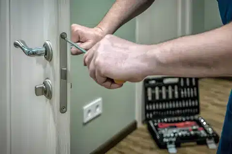 Burglary Repair Technician with tools installs a door lock